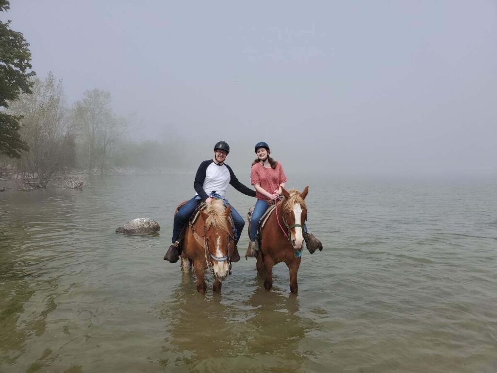 Couple on horseback in the water with fog