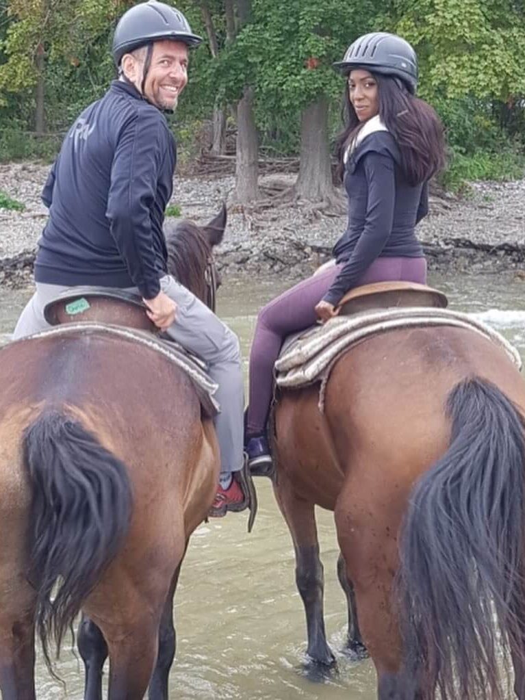 Couple turned looking backwards on horseback at the beach