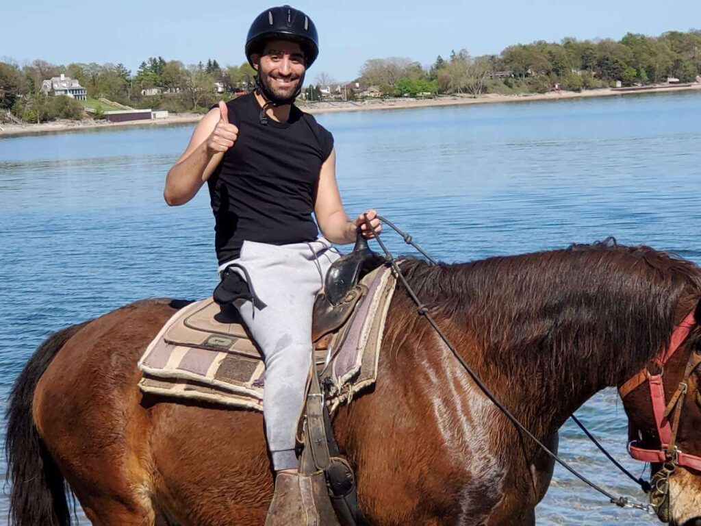 Man from Toronto giving thumbs up while sitting on a horse in the water