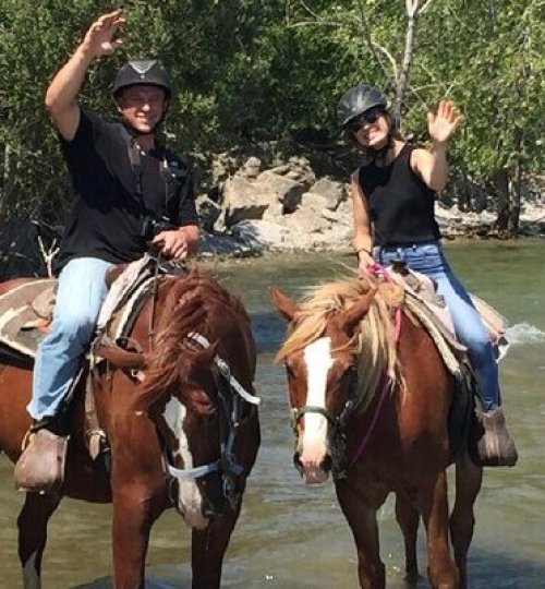 Couple horseback riding in water at the beach