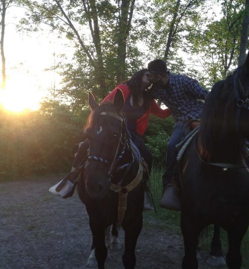 Couple kissing on horseback with the sunset