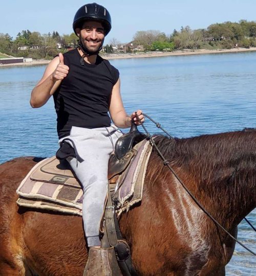 Man from Toronto giving thumbs up while sitting on a horse in the water